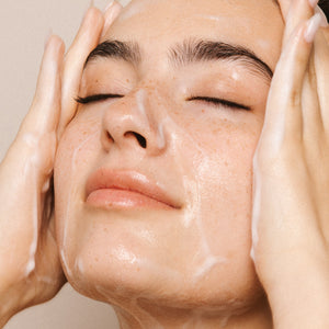 Vrouw smeert een Prescription Skincare cleanser op haar gezicht en geniet van het moment met haar ogen dicht